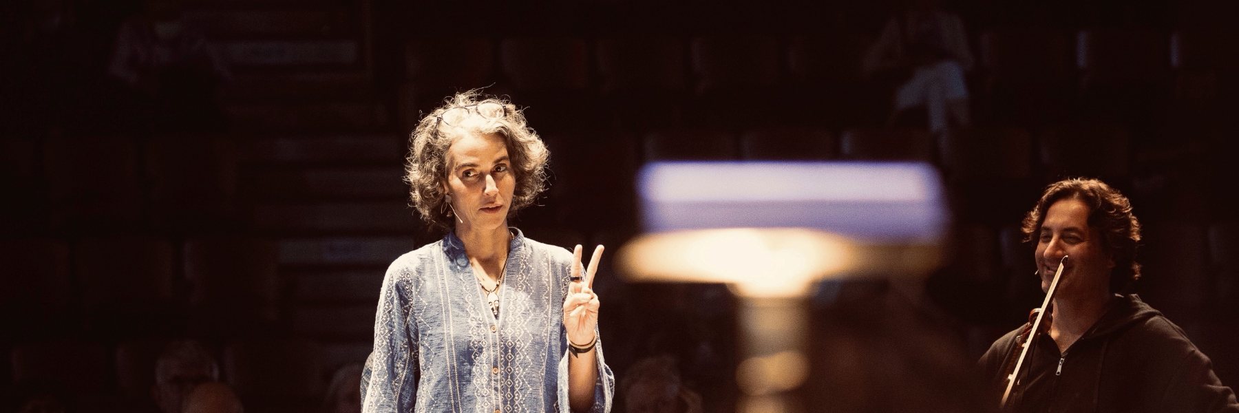 Clarice Assad holding up two fingers to the orchestra