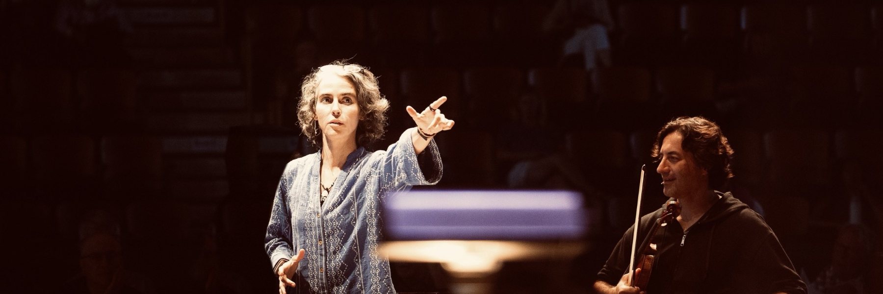 Clarice Assad pointing out across the orchestra to give a cue